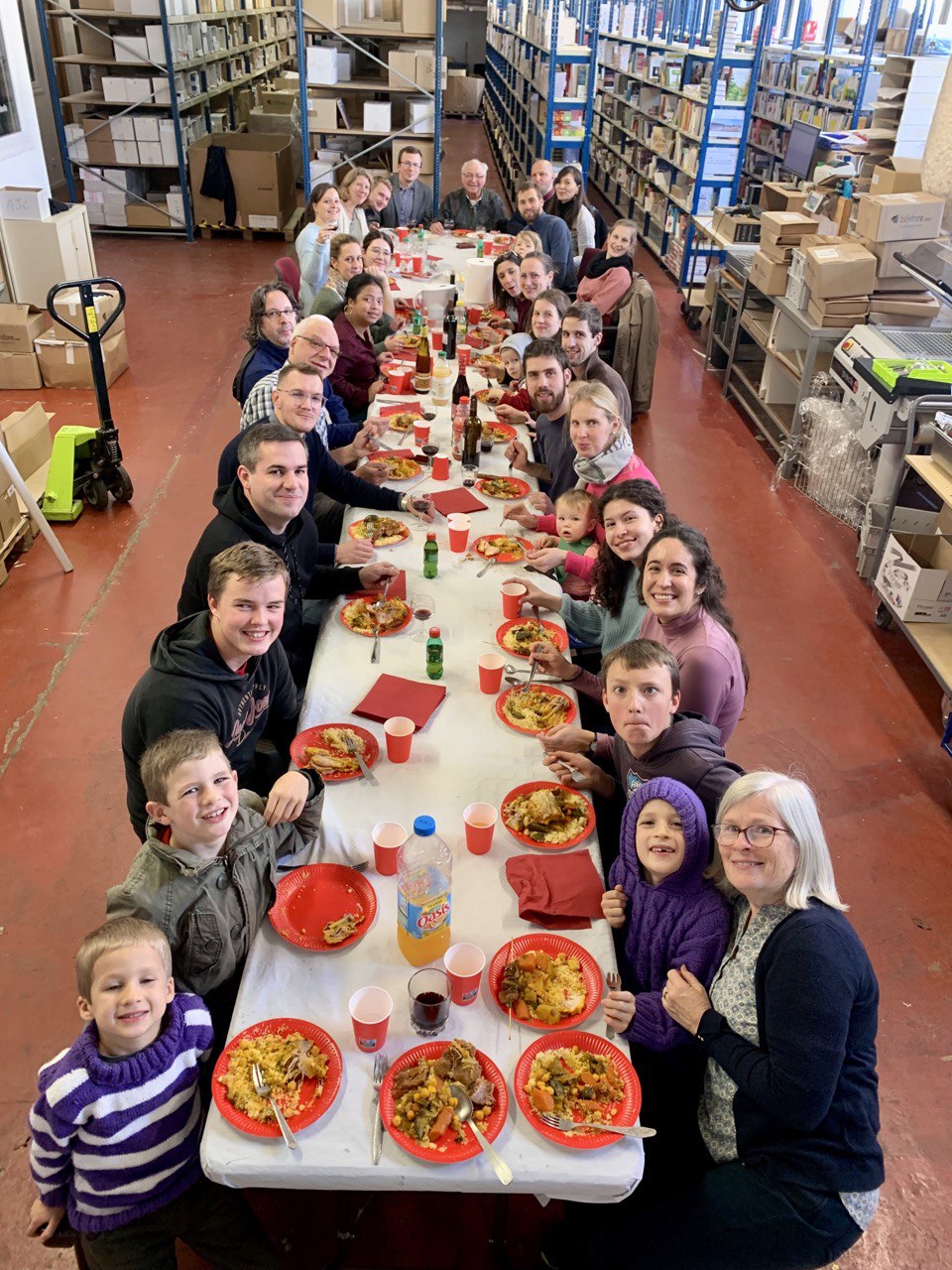 The BLF team gathered around a meal table between bookshelves in its warehouse